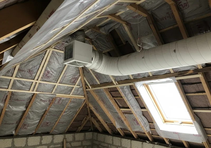 Pose d'une membrane pare-vapeur et d'une bouche de VMC sous les combles d'une maison à Saint-Malo